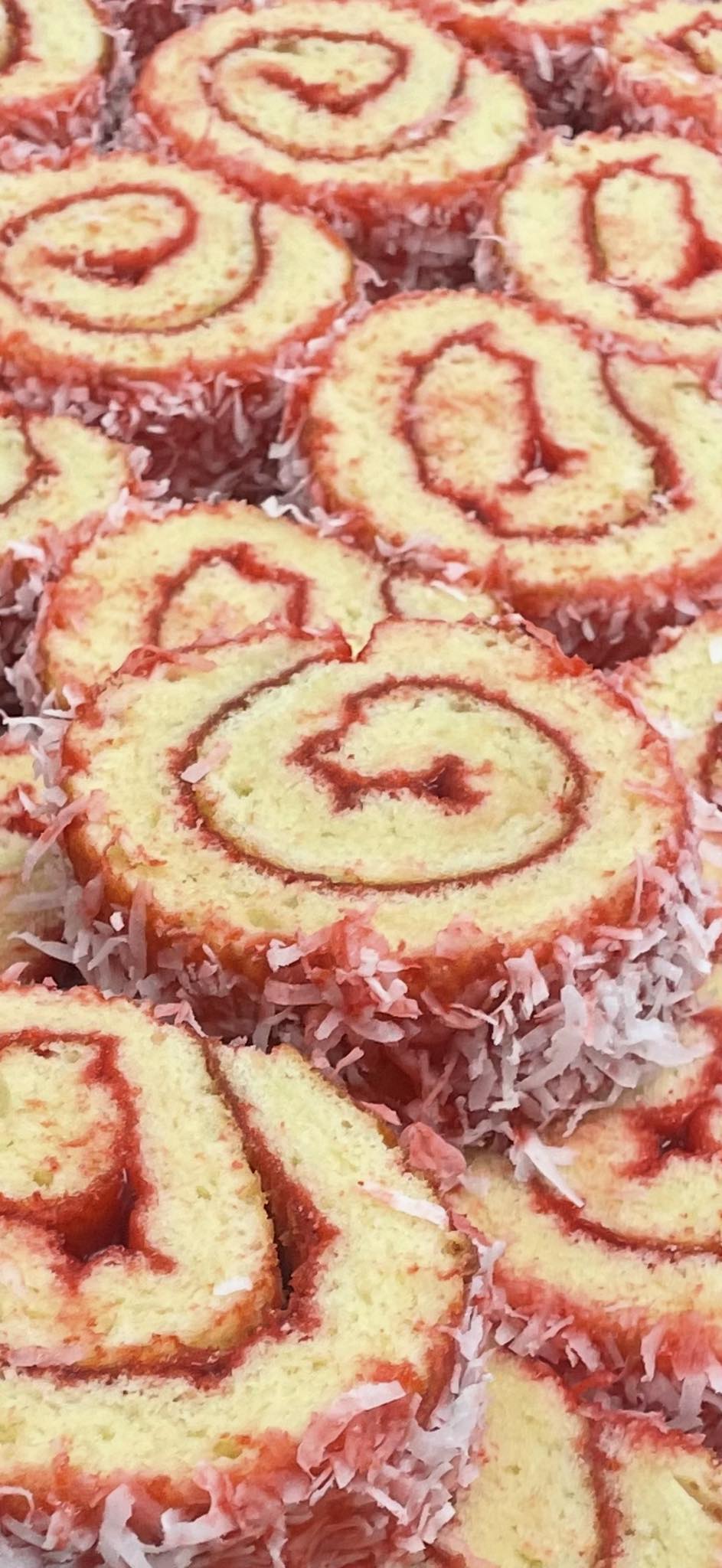A close-up shows numerous red-swirled cake slices generously dusted with shredded coconut.