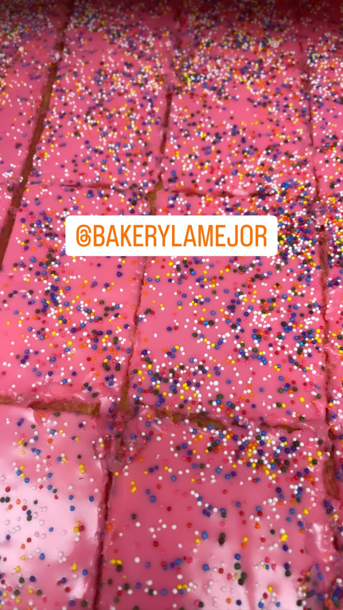 The image shows pink frosted dessert squares covered in colorful sprinkles, featuring the text '@BAKERYLAMEJOR'.
